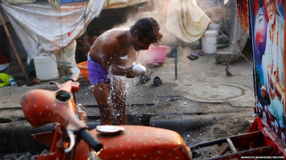 A migrant labourer bathes near the construction site of a hotel on a cold winter morning in Delhi