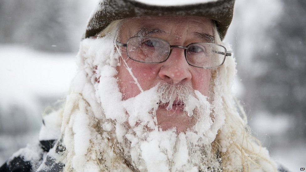 A man takes a break from blowing snow off of his driveway at his home in the US state of Michigan
