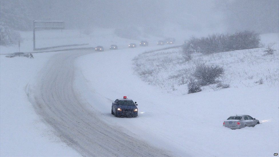 A Michigan State Trooper checks on a motorist who slid off the I-75 in Clarkston on Sunday