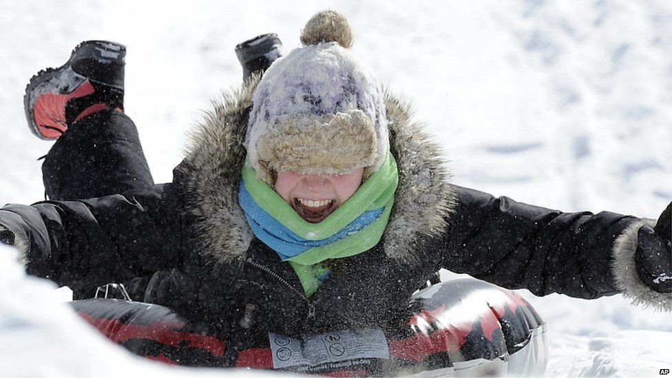 A girl takes a day off from school by taking advantage of an overnight snowfall to slide down a hill in Pringle, Pennsylvania
