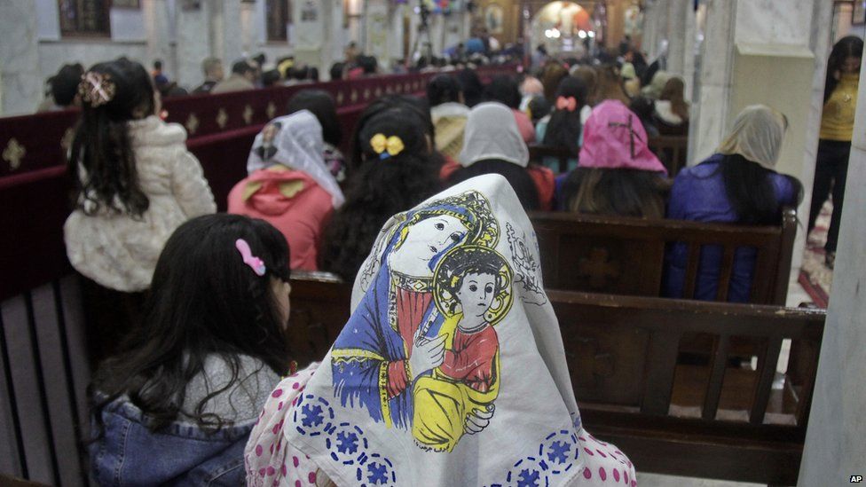 worshippers in church with woman wearing headscarf portraying Mary and Jesus