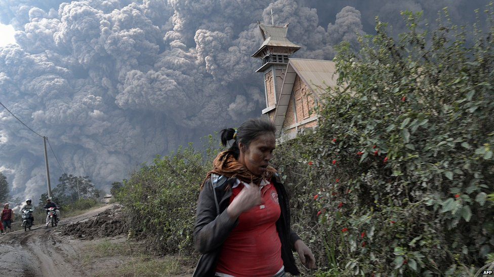 A woman flees as Mount Sinabung erupts near Bekerah village, in Karo district, North Sumatra, on February 1