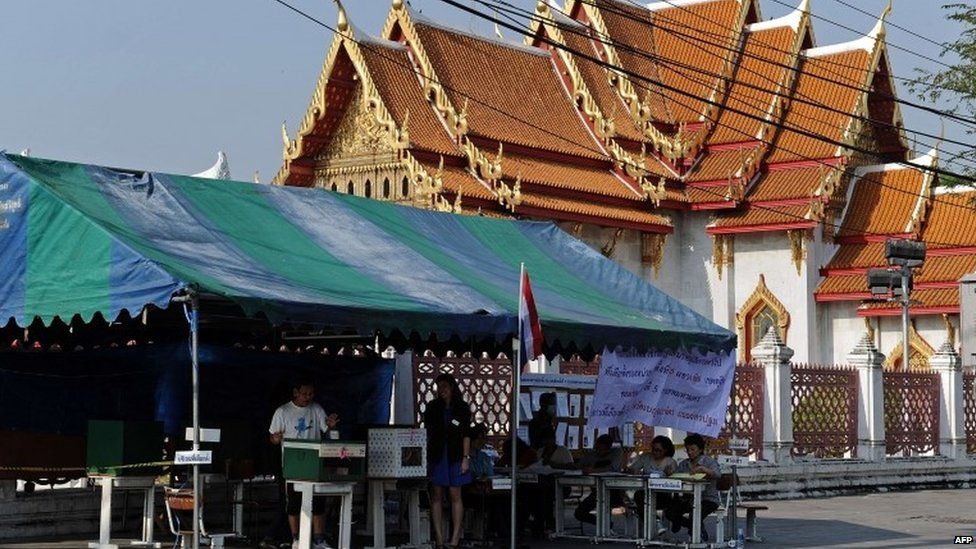 A Thai voter (L) casts his vote at an outdoor polling station in central Bangkok