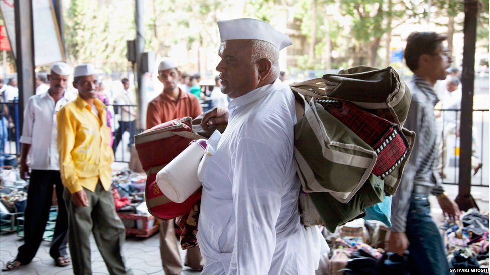 A dabbawala with several bags slung over his shoulder