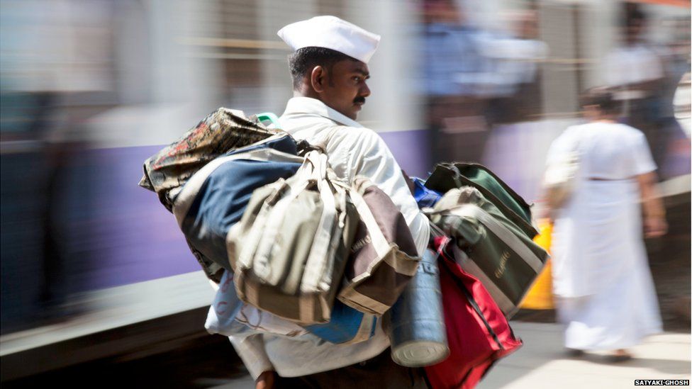 A Dabbawala carrying bags of tiffin tins on his shoulder