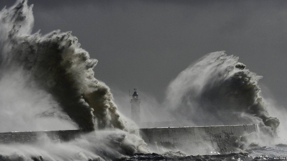 Large waves hit the lighthouse and harbour at high tide at Newhaven in Sussex