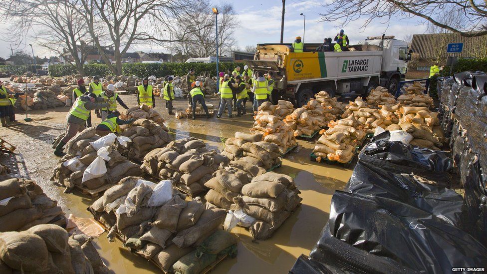 Volunteers and charities fill sandbags before they are distributed in Egham, west of London.