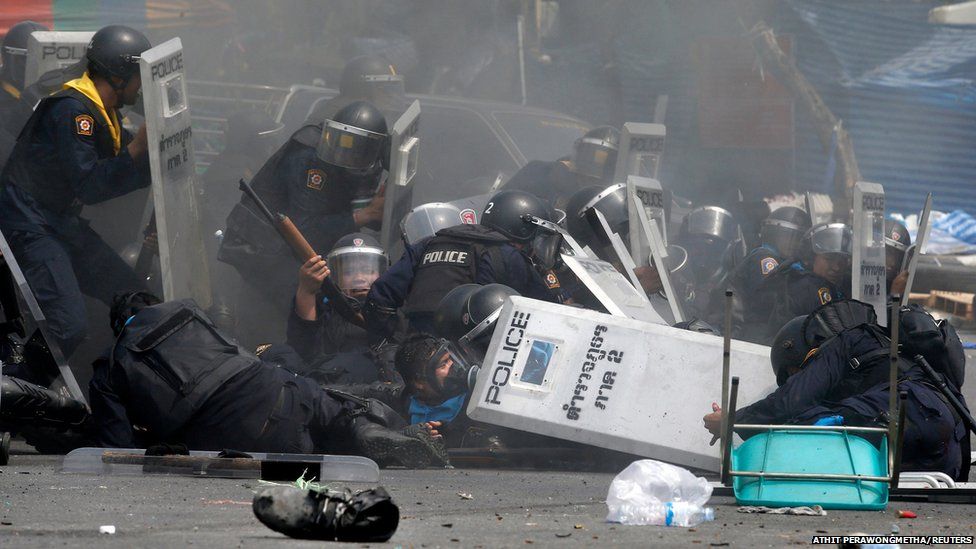 Thai police officers react after an explosion during clashes