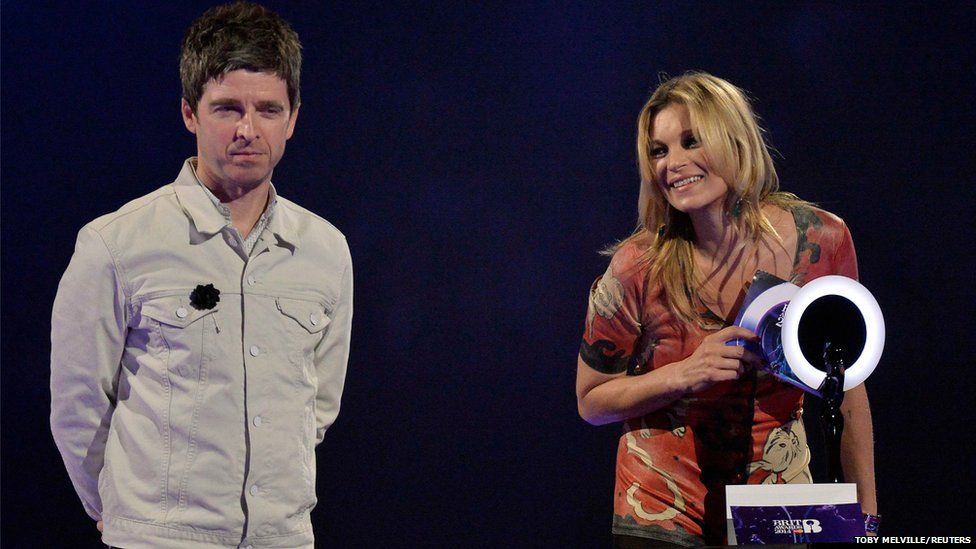 Model Kate Moss accepts the British Male Solo Artist award on behalf of David Bowie as musician Noel Gallagher looks on