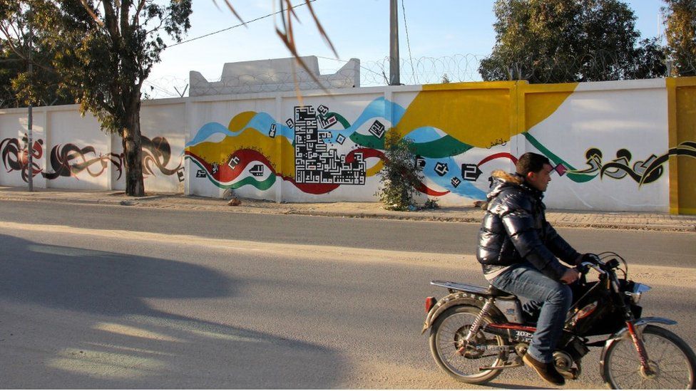 A man rides past Tunisia's longest street mural i in Kasserine
