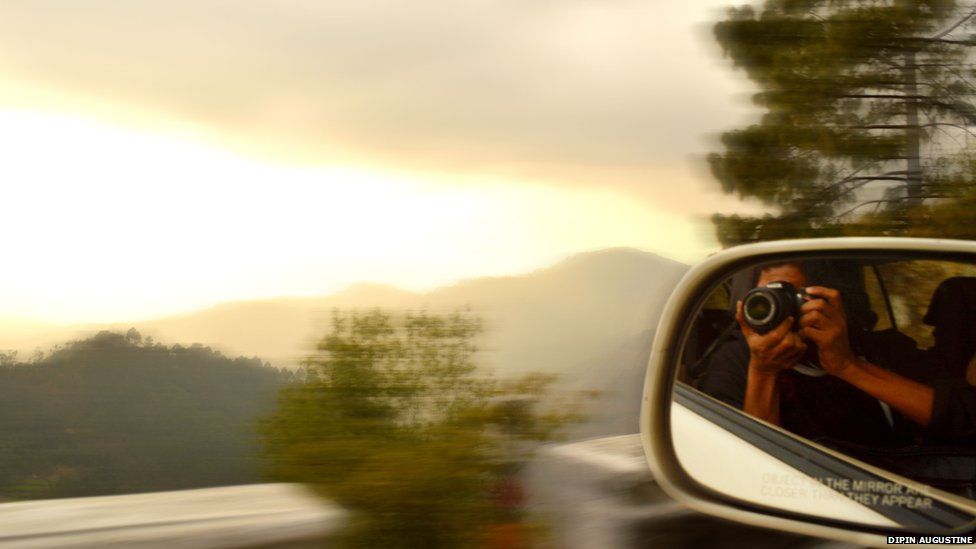 Photographer in car wing mirror