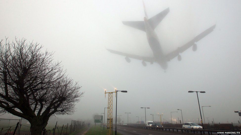 An aircraft lands in fog at Heathrow Airport