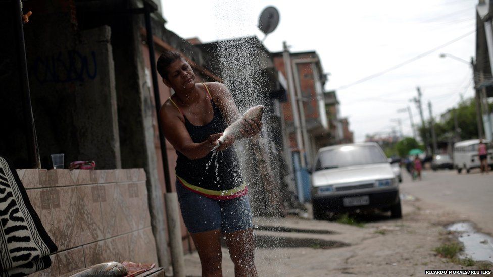 A woman cleans a fish on the streets of the Mare slums complex, Rio de Janeiro