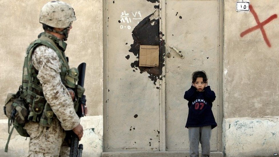 An Iraqi girl covers her ears as a US Marine patrols the Iraqi town of Falluja. Photo: 2005