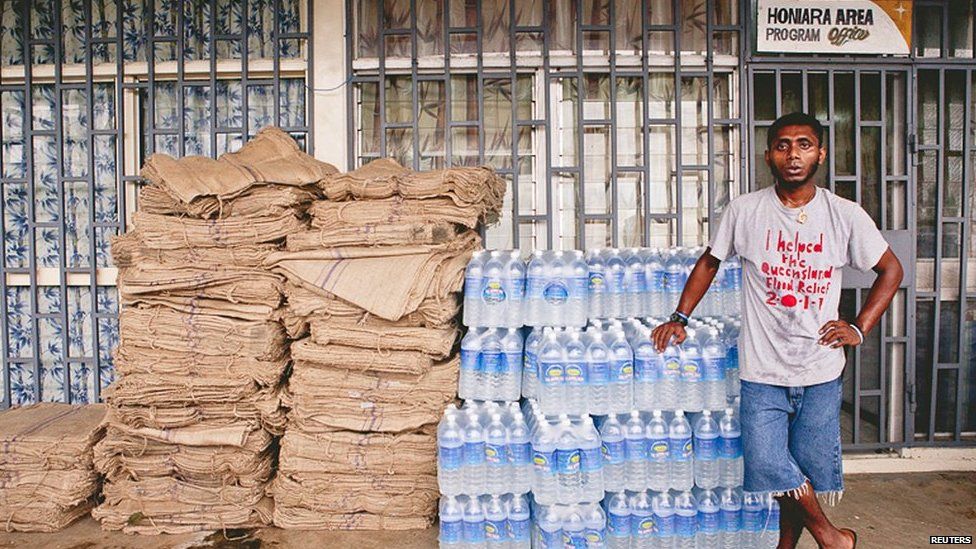 A relief worker stands next to supplies of blankets and water at a distribution centre after severe flooding in the capital Honiara in the Solomon Islands in this picture released by World Vision on 6 April, 2014