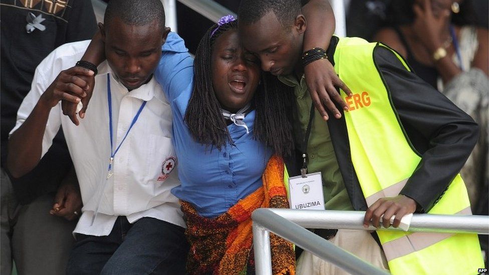 A woman is helped out of the Amahoro stadium, in Kigali, on April 7,2014, during a ceremony marking the 20th anniversary of Rwanda"s genocide