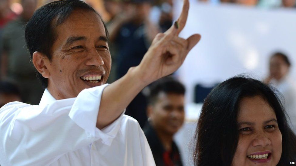 Jakarta Governor Joko Widodo and presidential candidate of the opposition Indonesian Democratic Party of Struggle (PDI-P) accompanied by his wife Iriana Widodo (R), displays his inked finger after casting his ballot during the legislative election in Jakarta on 9 April, 2014