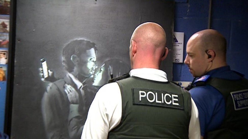 Police officers viewing the Banksy artwork