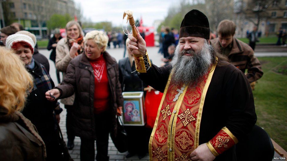 Ukrainian Orthodox priest sprinkles holy water on believers outside a government building in Donetsk, Ukraine, on 20 April 2014