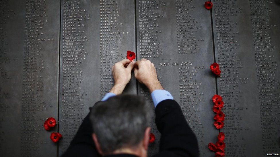 A man places a poppy flower into the World War I Wall of Remembrance on ANZAC Day at the Australian National War Memorial in Canberra on 25 April, 2014