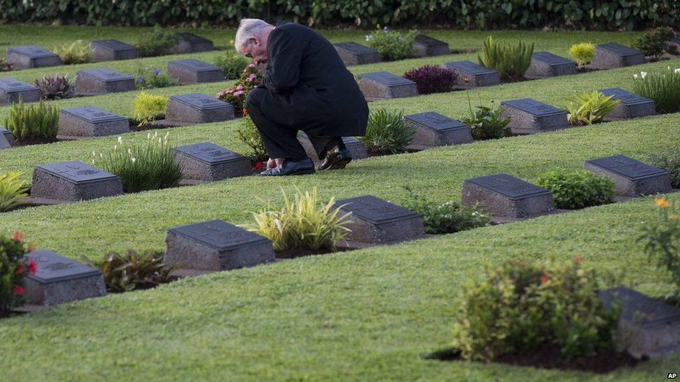 A visitor to the Jakarta War Cemetery places a poppy on a headstone following the ANZAC Day dawn service in Jakarta, Indonesia, on Friday, 25 April, 2014