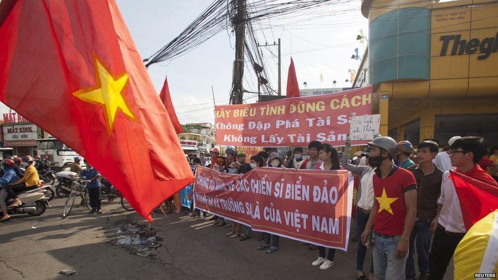 Workers hold banners, which read, "Please protest in the right way" and "We are looking at soldiers on islands, and the Paracels and the Spratlys belong to Vietnam", during a protest in an industrial zone in Binh Duong province on 14 May, 2014