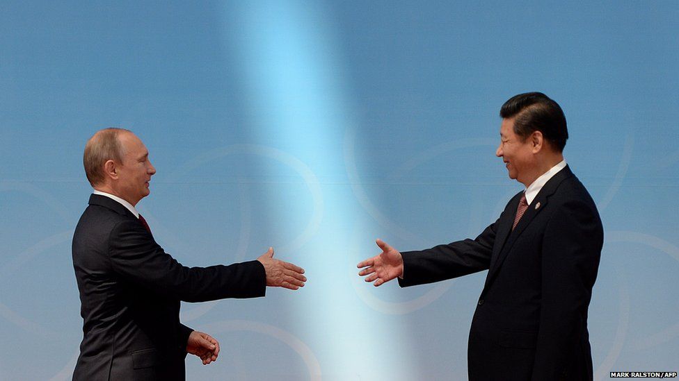 Russian President Vladimir Putin (left) is greeted by Chinese President Xi Jinping
