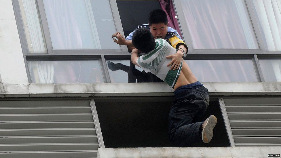A police officer grabs a man who tried to jump off the seventh floor of a hotel
