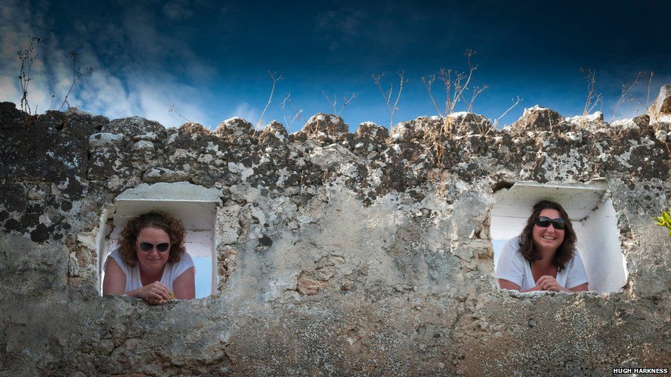 Portrait of two women looking through a wall