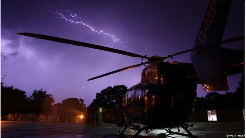 Lightning seen in the sky over a police helicopter which is on the ground