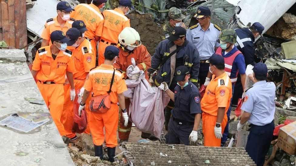 Rescue workers and firefighters search through the wreckage in Penghu on 24 July 2014
