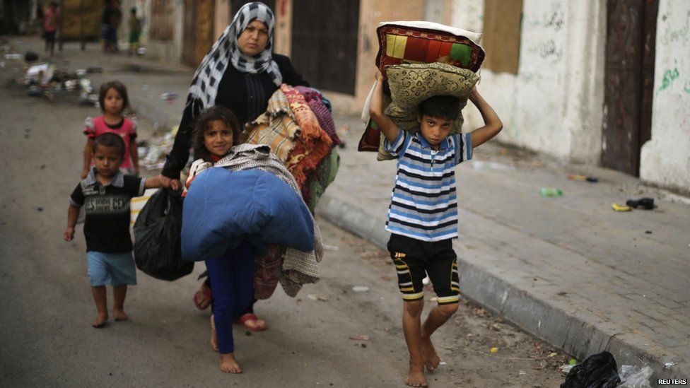 Palestinians carry their belongings as flee their house from what witnesses said were Israeli air strikes, in Gaza City