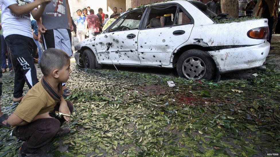 A Palestinian boy looks at a damaged car at the scene of an explosion at a public garden in Gaza City July 28, 2014.