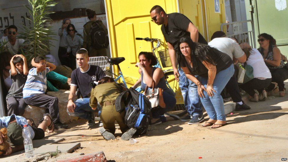 Israeli residents take cover from a rocket attack during the funeral of Israeli soldier Corporal Meidan Maymon Biton, 20, at a cemetery in Netivot - 29 July 2014