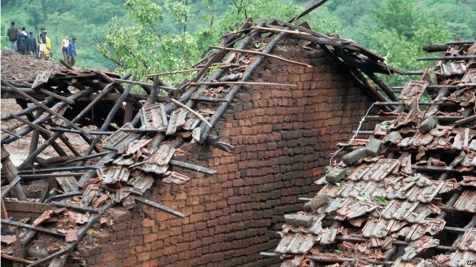 Homes stand damaged as rescuers work at the site of a landslide in Malin village, in the western Indian state of Maharashtra, Wednesday, July 30, 2014