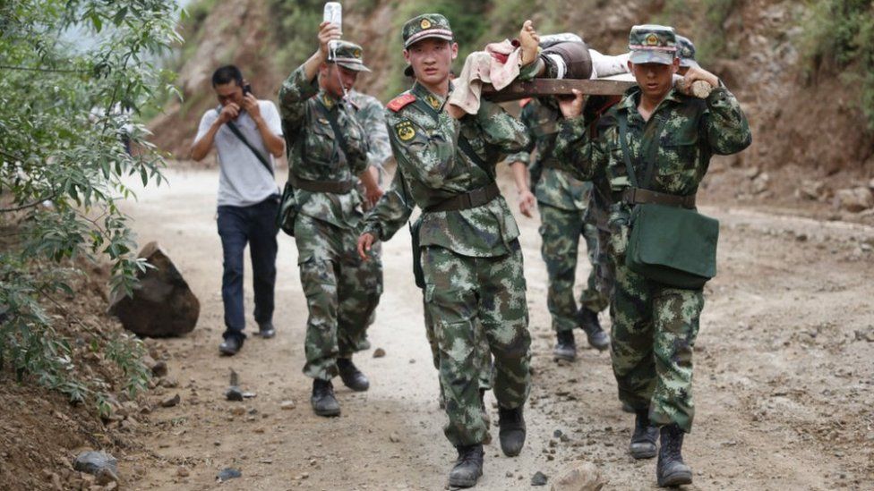 Chinese rescue workers carry an injured resident on a stretcher after the earthquake in Yunnan province - 3 August 2014