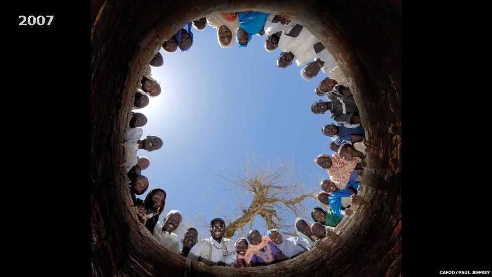 People pictured looking down a well being dug in Khamsa Dagiag camp in Darfur, Sudan - 2007