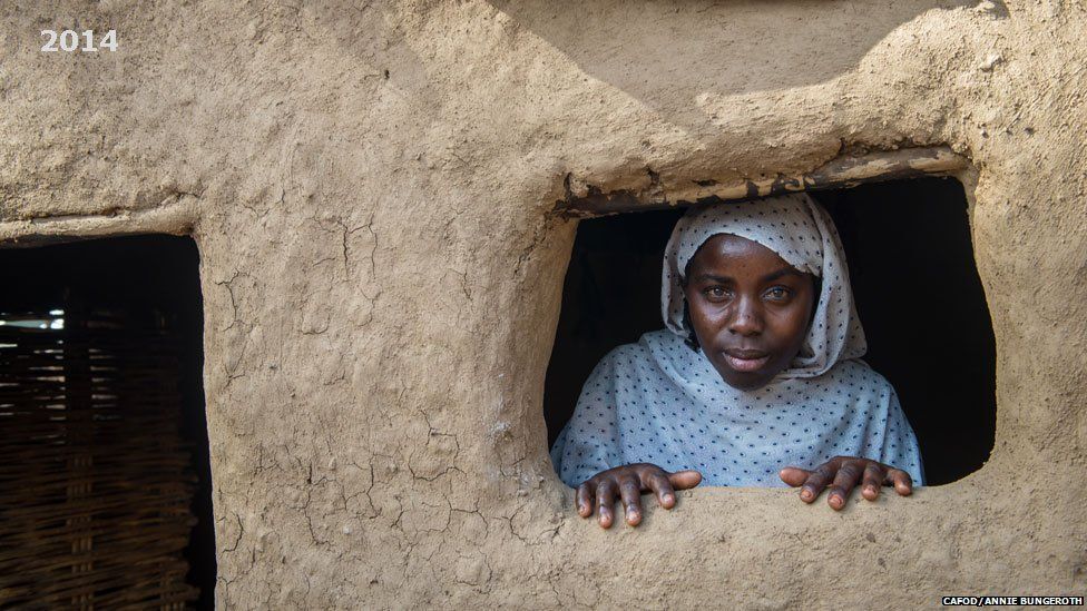 Amina looking out of the window of her house in Khamsa Dagiag camp in Darfur, Sudan - 2014