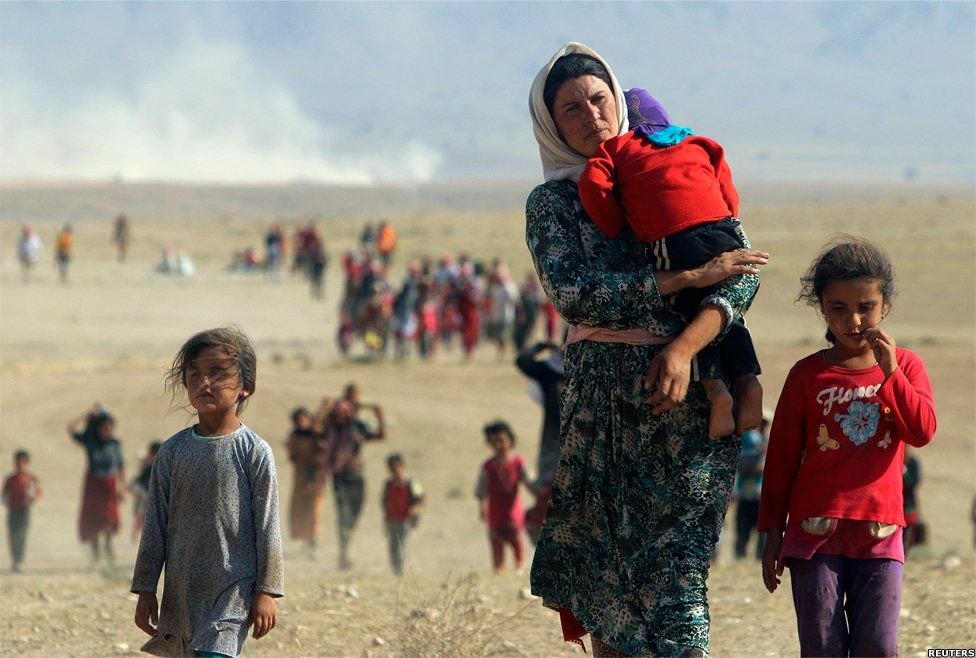 Displaced people from the minority Yazidi sect walk towards the Syrian border, on the outskirts of Sinjar mountain