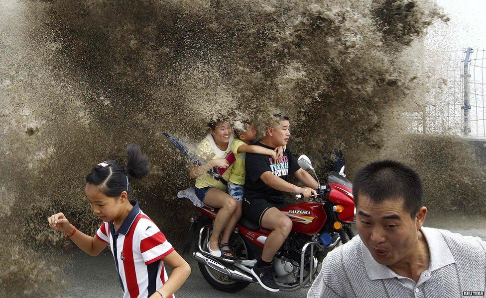 Visitors try to escape the waves caused by a tidal bore in China
