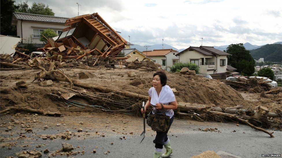 A local resident visits a landslide site to check if her house are damaged by a landslide caused by torrential rain on August 21, 2014 in Hiroshima, Japan