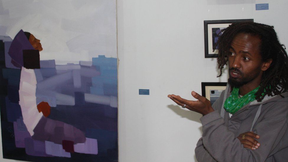 Leikun Nahusenay in front of a work by Kibrom Gebremedhin at the Guramayle Art Center in Addis Ababa, Ethiopia