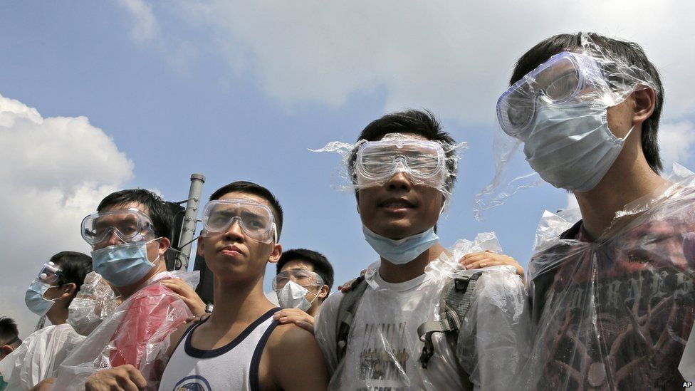 Protesters wear masks and goggles to protect themselves from pepper spray while blocking a police car outside the government headquarters in Hong Kong, Sunday on 28 September 2014