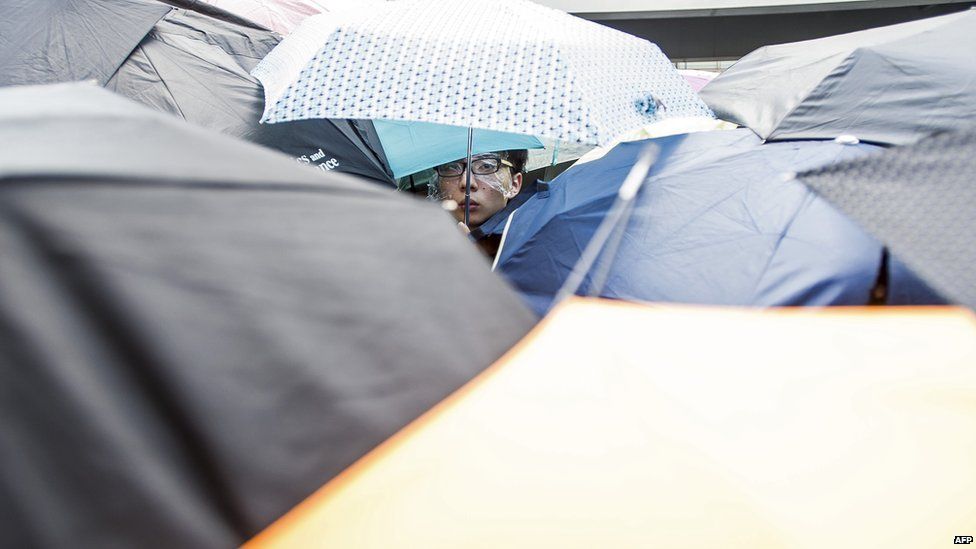 A protester looks on from under umbrellas used to protect demonstrators from pepper spray during a demonstration at the government headquarters in Hong Kong on 27 September, 2014