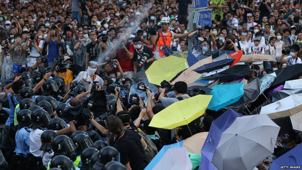 Police (L) fire pepper spray towards pro-democracy demonstrators near the Hong Kong government headquarters on 28 September 2014.