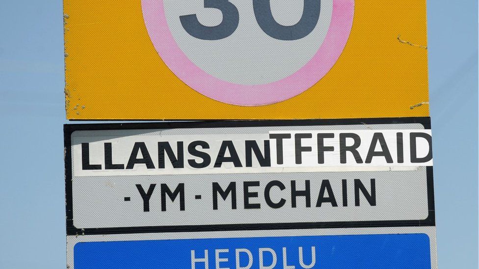 A road sign where the name of the village is spelt with a 'T'.