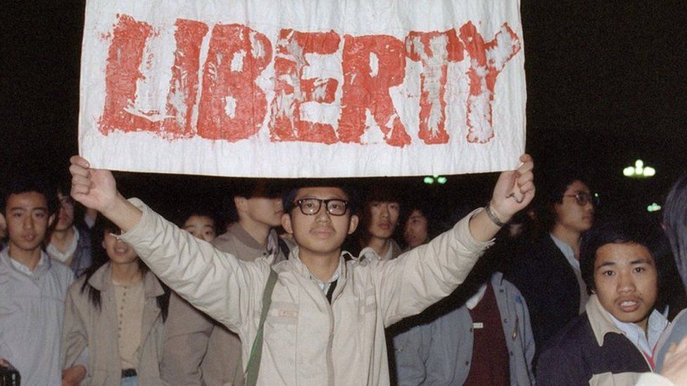 A student displays a banner with one of the slogans chanted by the crowd in Tiananmen Square on 22 April 1989