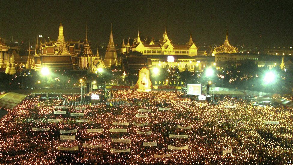 Thai people light the candles on the Royal Grounds, outside the Grand Palace