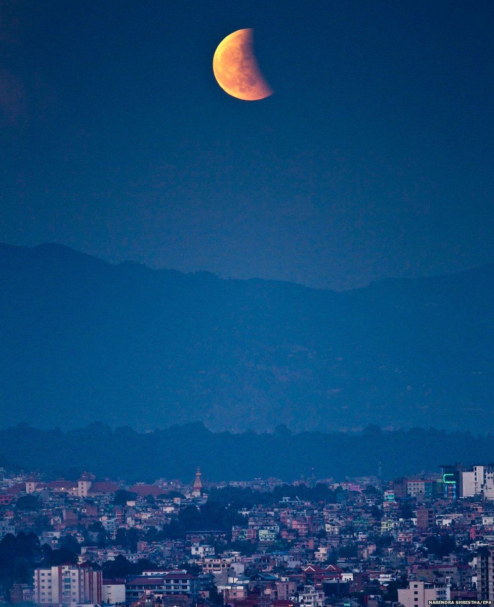The moon is seen glowing red as its rise during a total lunar eclipse from Kathmandu, Nepal
