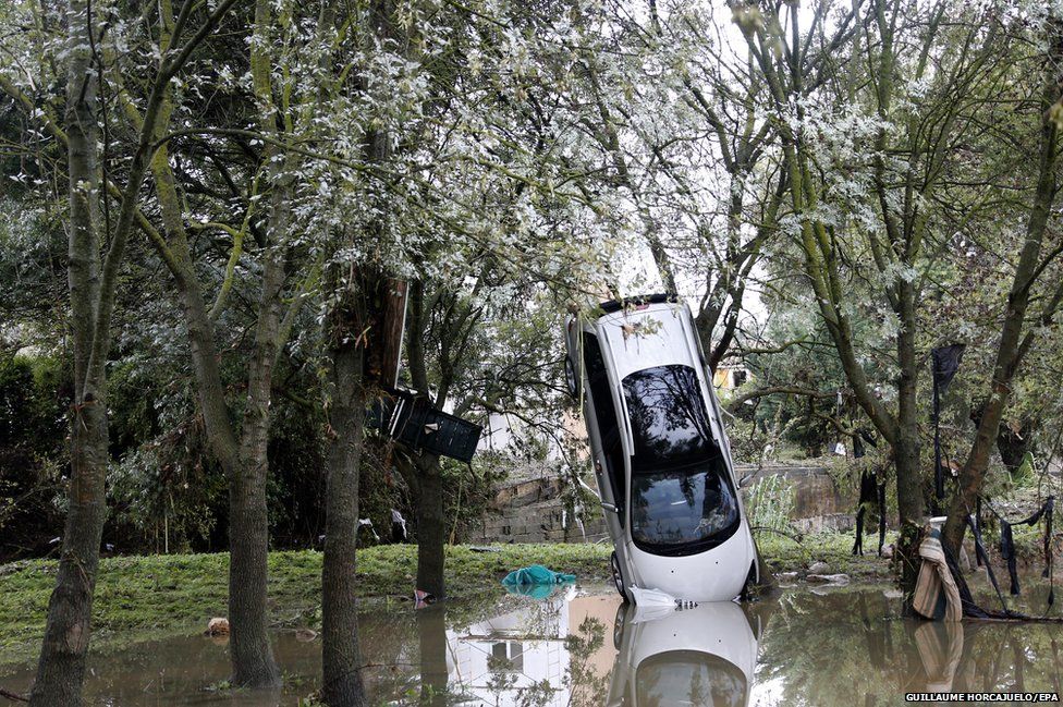 A car is propped up against a tree following heavy floods in Grabels, near Montpellier, Southern France